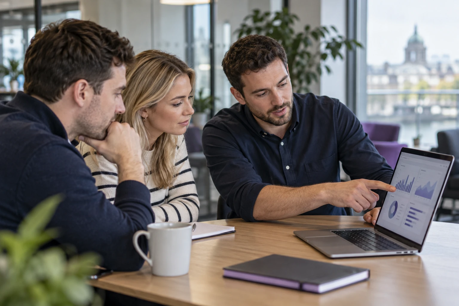 A consultant guiding two colleagues through a reporting dashboard on a laptop.